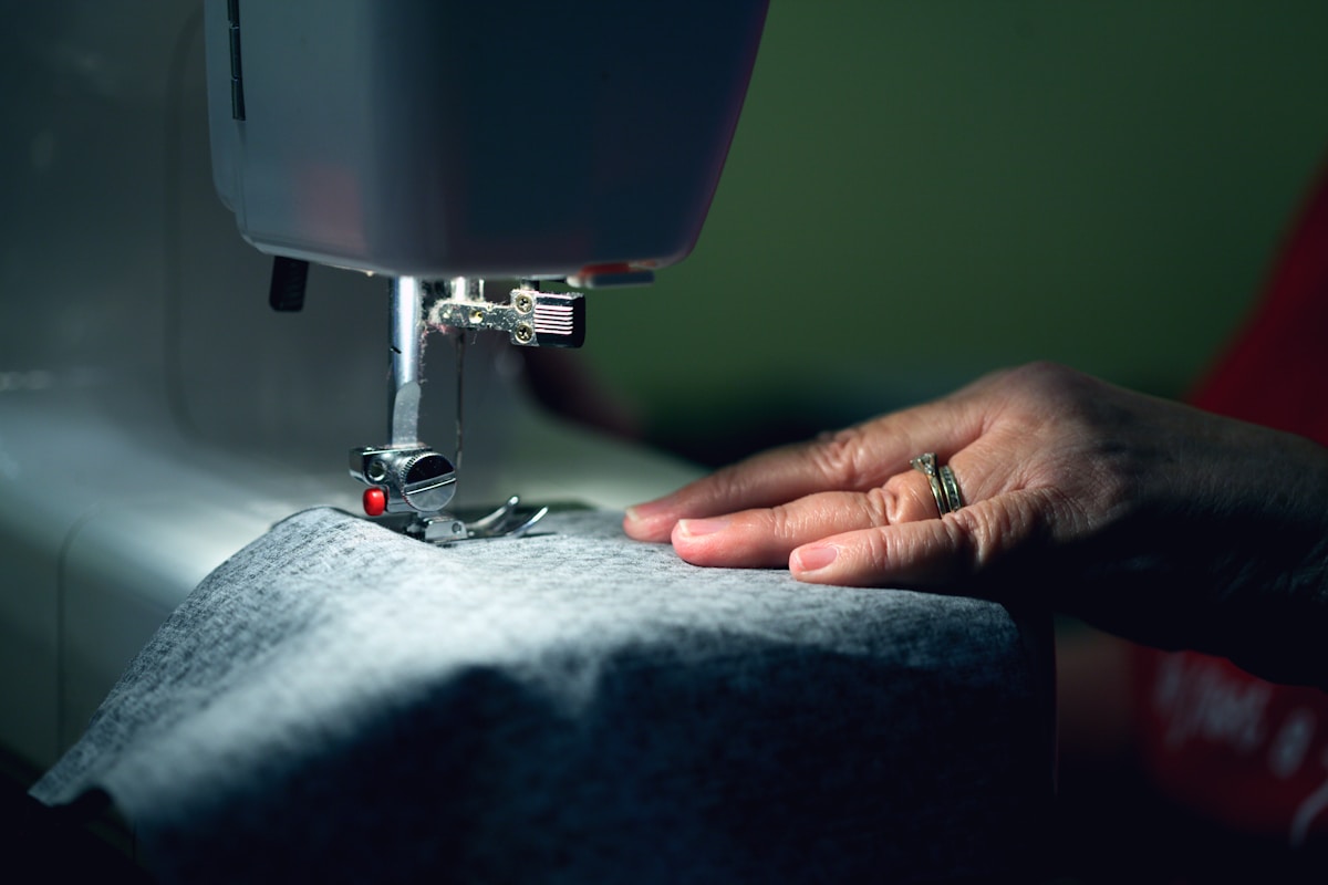 Hand an der Stickmaschine beim Nähen von Stoff